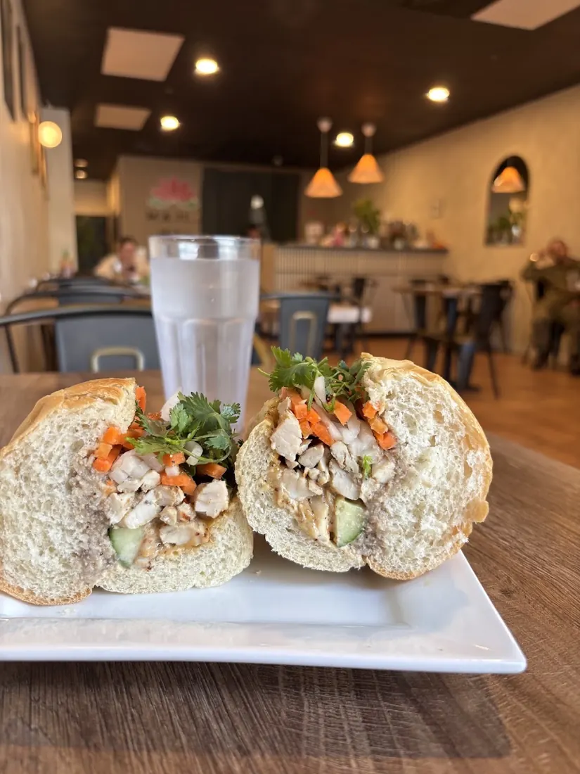 A halved banh mi on a white plate in the Mama Mai dining room